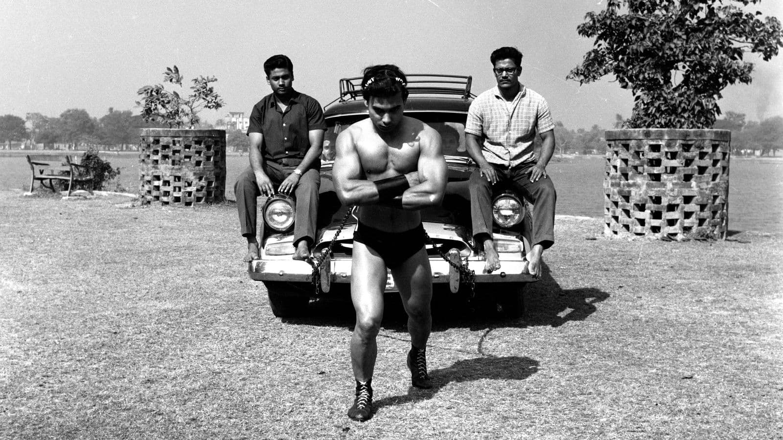 Bikram Choudhury chained at the waist pulling a car with passengers